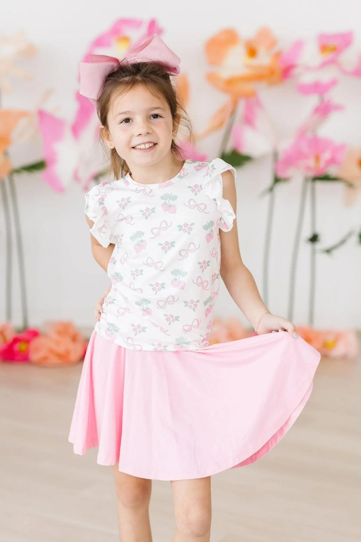 Girls pink ruffle tee shirt with short sleeves worn by young girl with bow headband