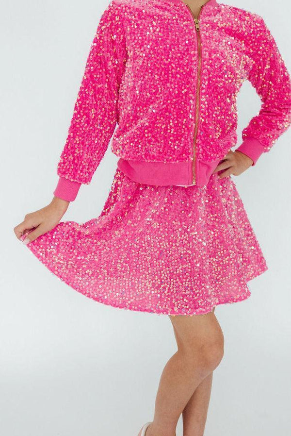 Girl wearing girls pink sequin skort and matching jacket posing with hand holding skort