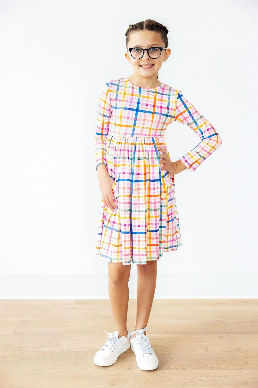 Girls plaid twirl dress in multicolor with long sleeves and pockets, worn by young girl