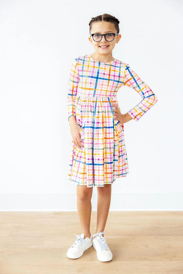 Girls plaid twirl dress in multicolor with long sleeves and pockets, worn by young girl