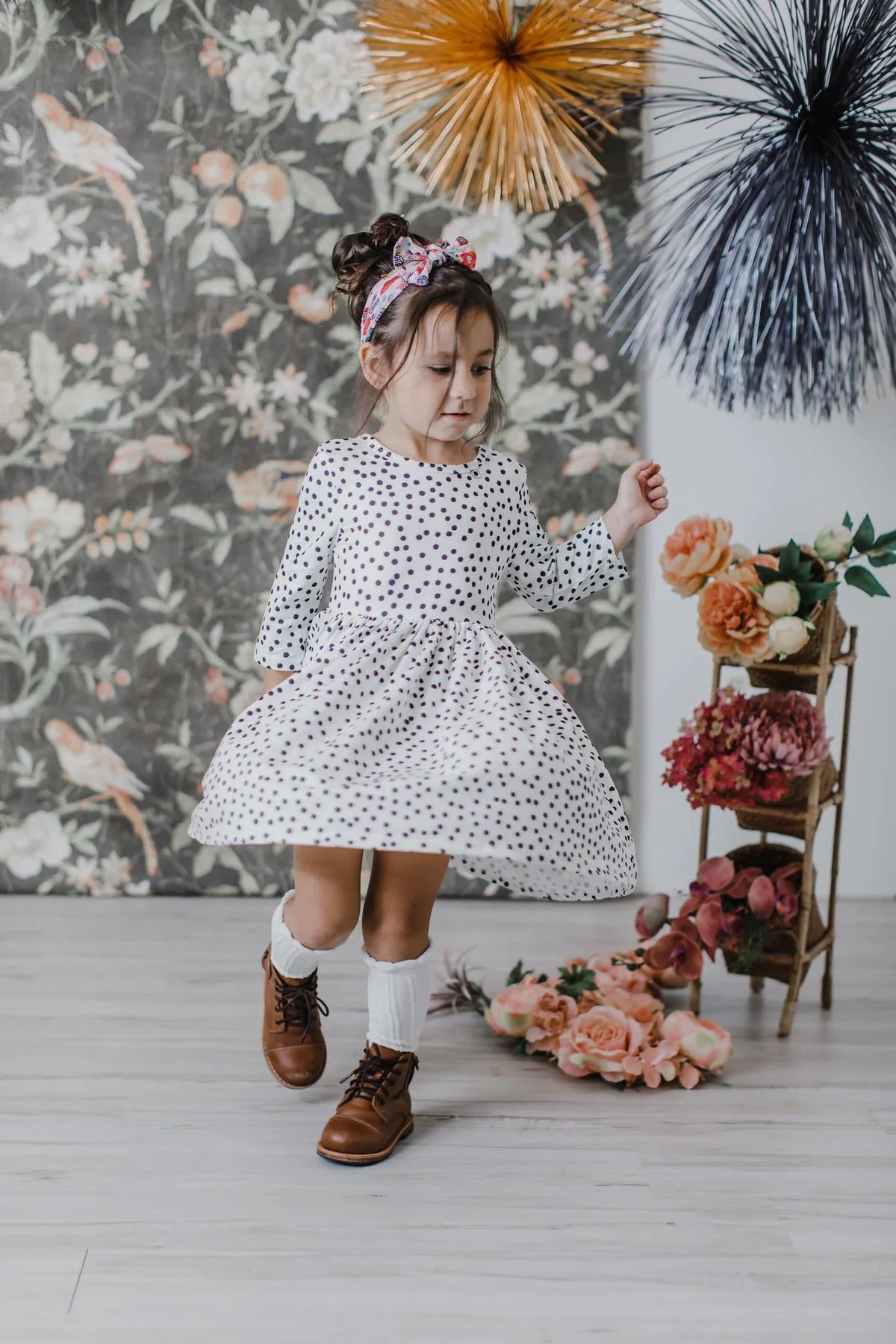 Young girl wearing white and black girls polka dot twirl dress with 3/4 sleeves dancing indoors