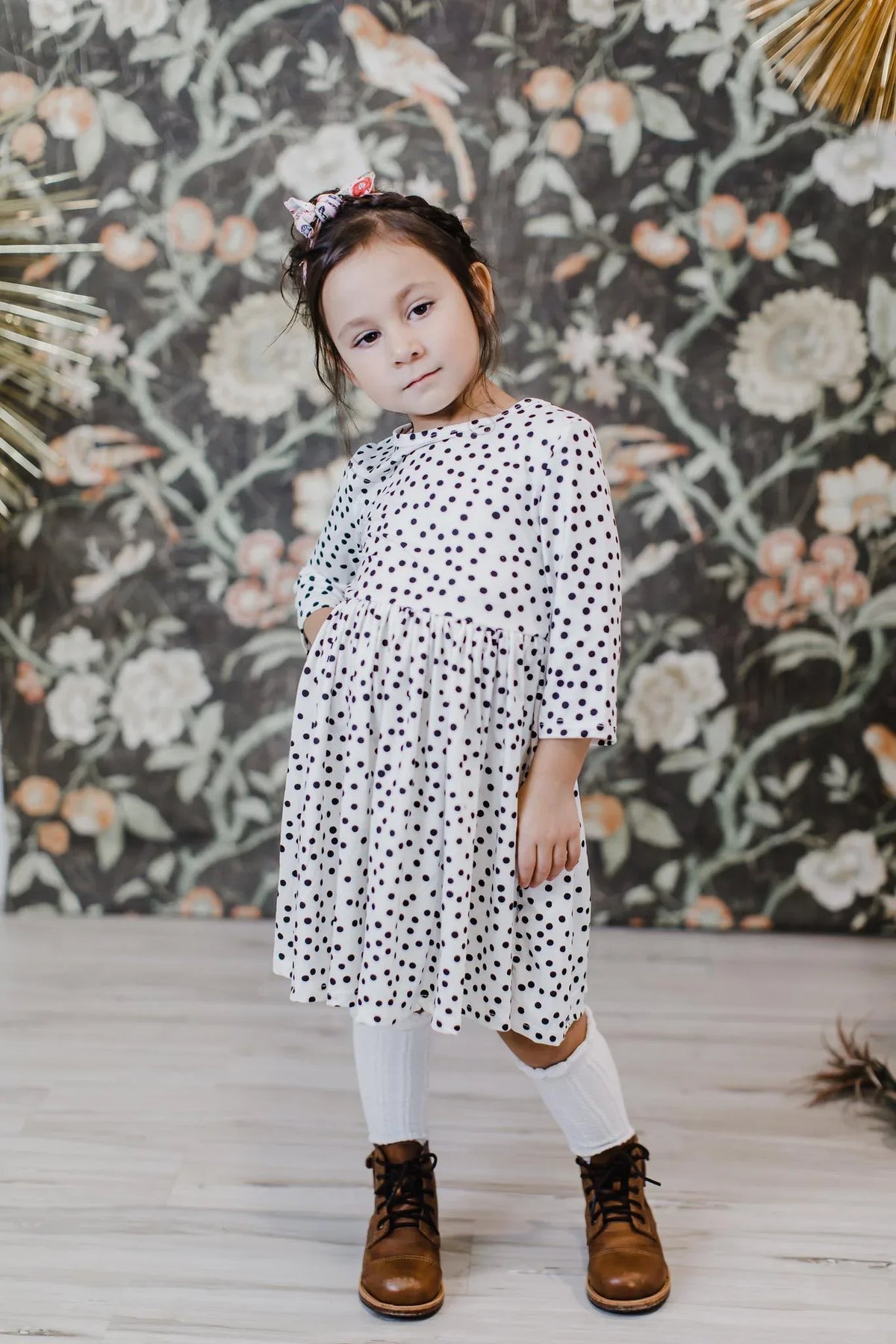 young girl wearing white and black girls polka dot twirl dress standing with hand on hip
