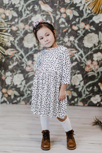 young girl wearing white and black girls polka dot twirl dress standing with hand on hip