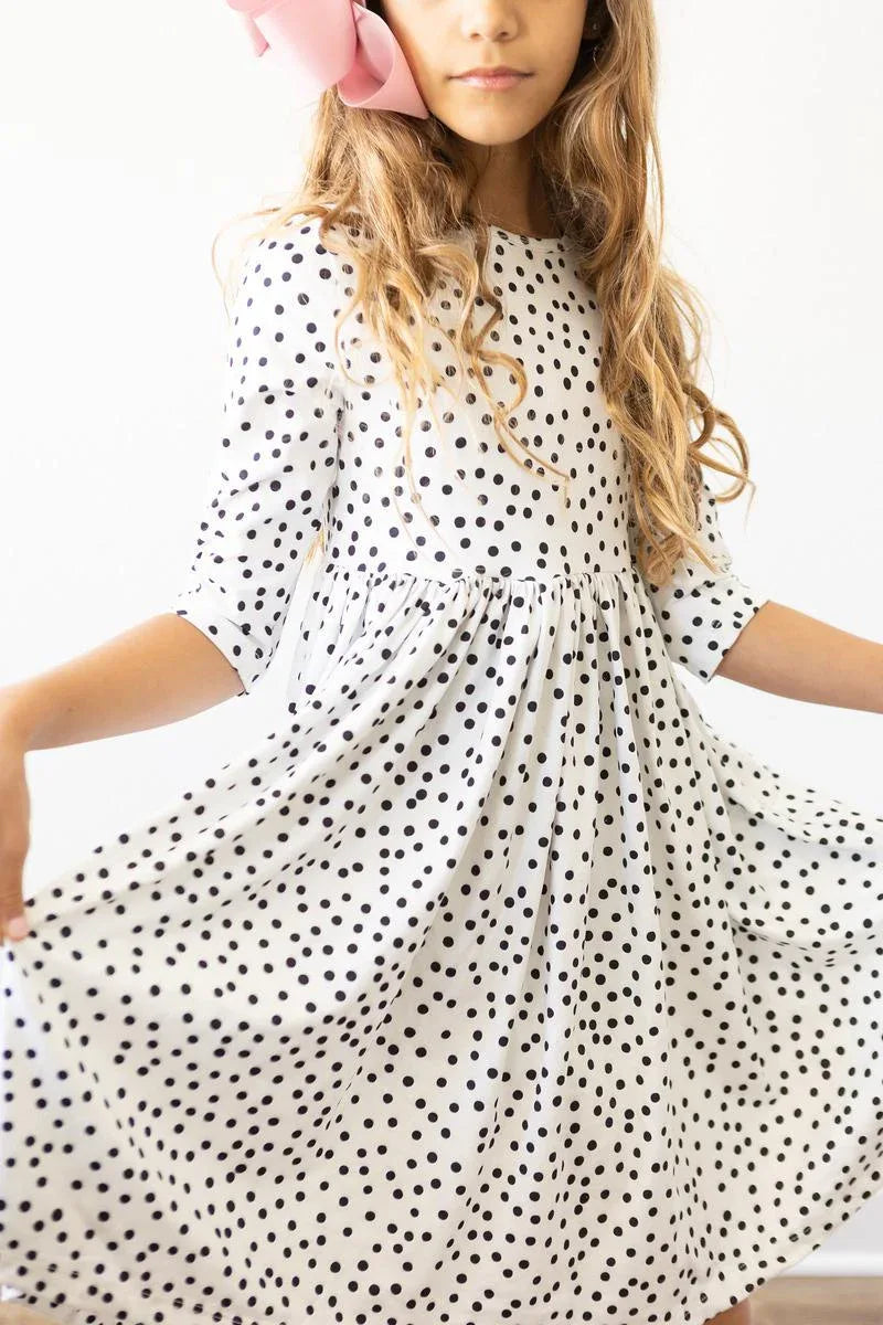 girl wearing white and black girls polka dot twirl dress with 3/4 sleeves spinning