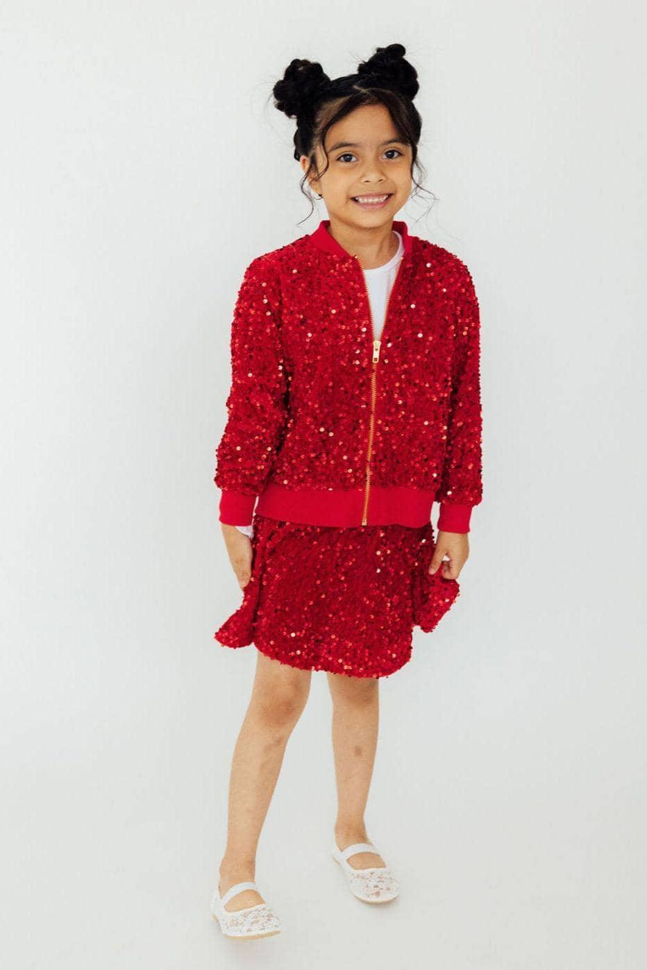 Girl wearing red sequin skort and matching jacket standing and smiling
