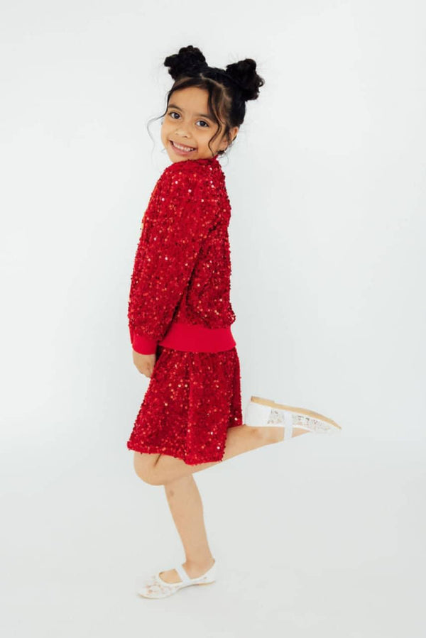 girl wearing red girls red sequin skort smiling and posing with one leg lifted