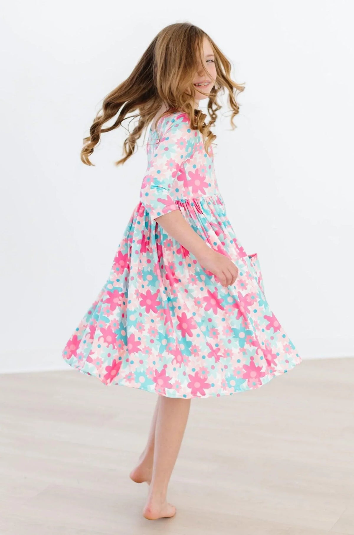 Girls retro floral twirl dress in pink and teal with 3/4 sleeves and pockets for kids
