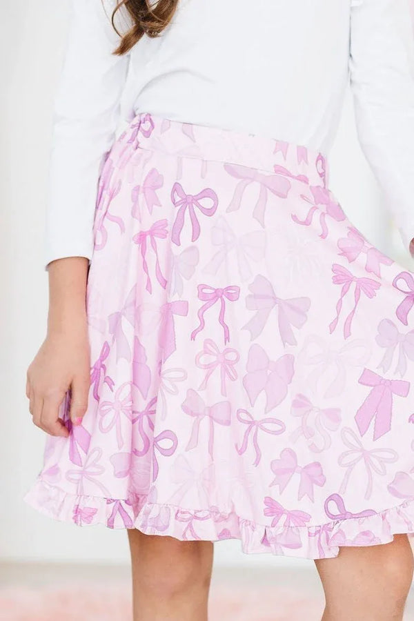 girl wearing pink bow print girls ruffle twirl skort holding hem while standing