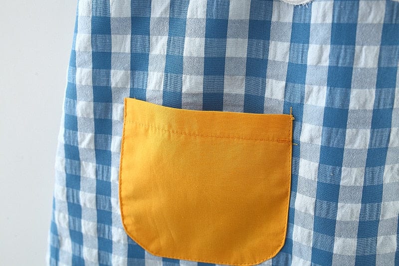Close-up of girls seersucker apple dress in blue and white check with a yellow front pocket for toddlers