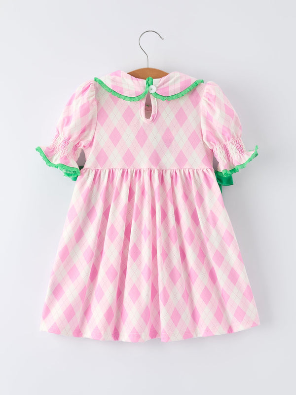 Pink and white argyle girls smocked golf dress with green trim for toddlers hanging on wooden hanger