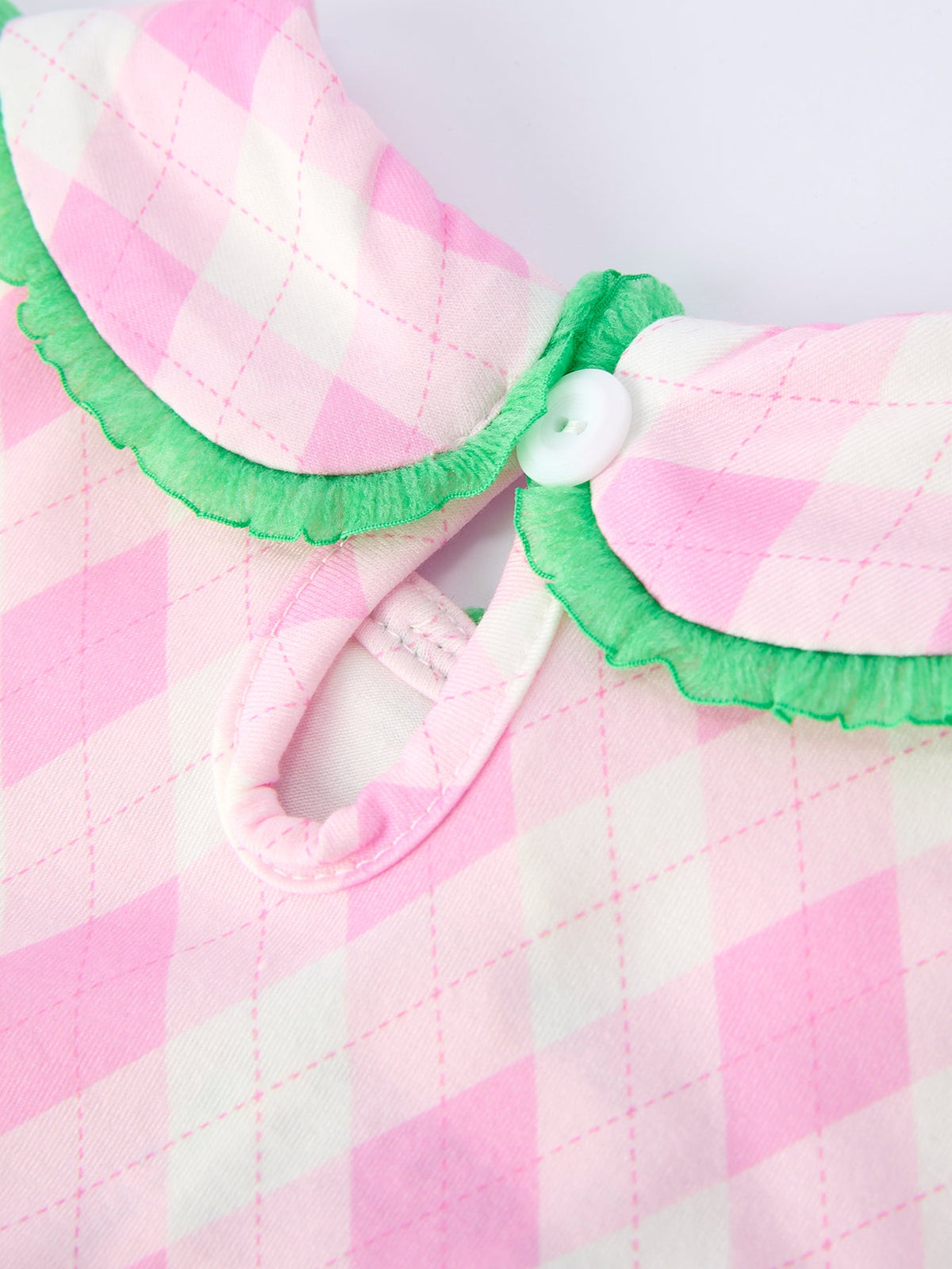 Close-up of pink and white checkered girls smocked golf dress collar with green trim and button detail for toddlers