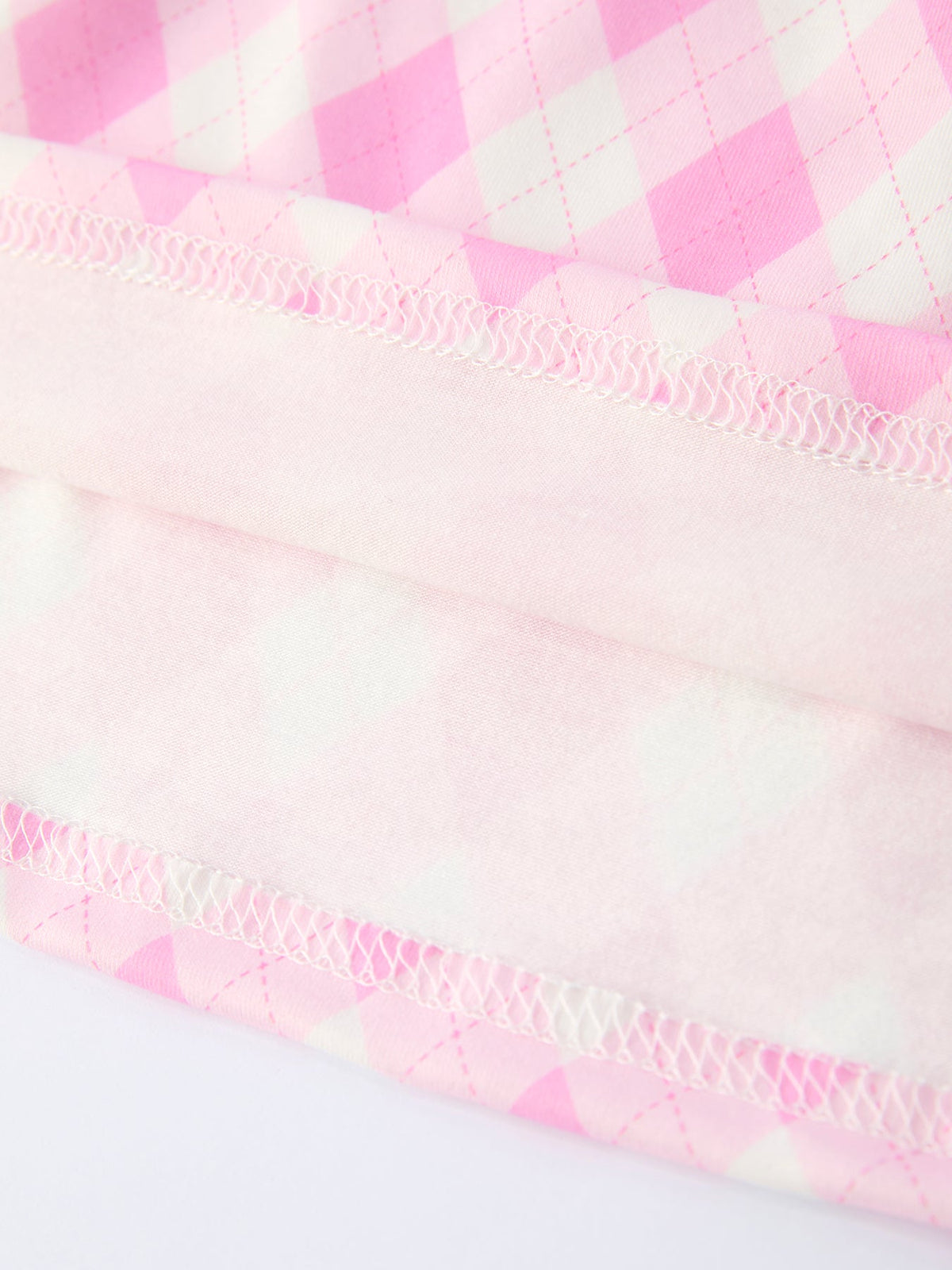 close-up of pink and white girls smocked golf dress fabric showing stitching and quilted pattern