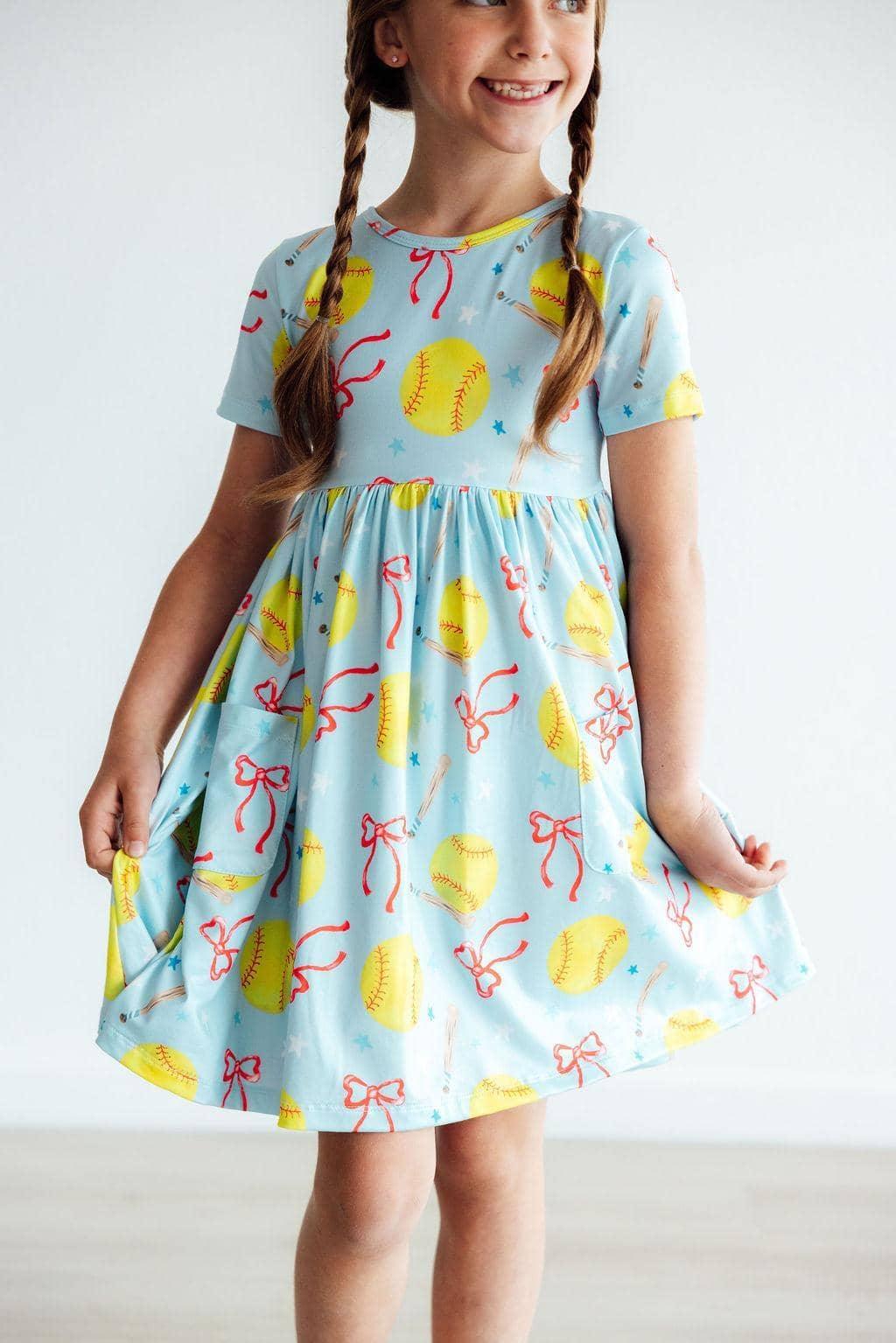 Girls light blue softball dress with yellow softball and red bow print, short sleeve twirl pocket dress