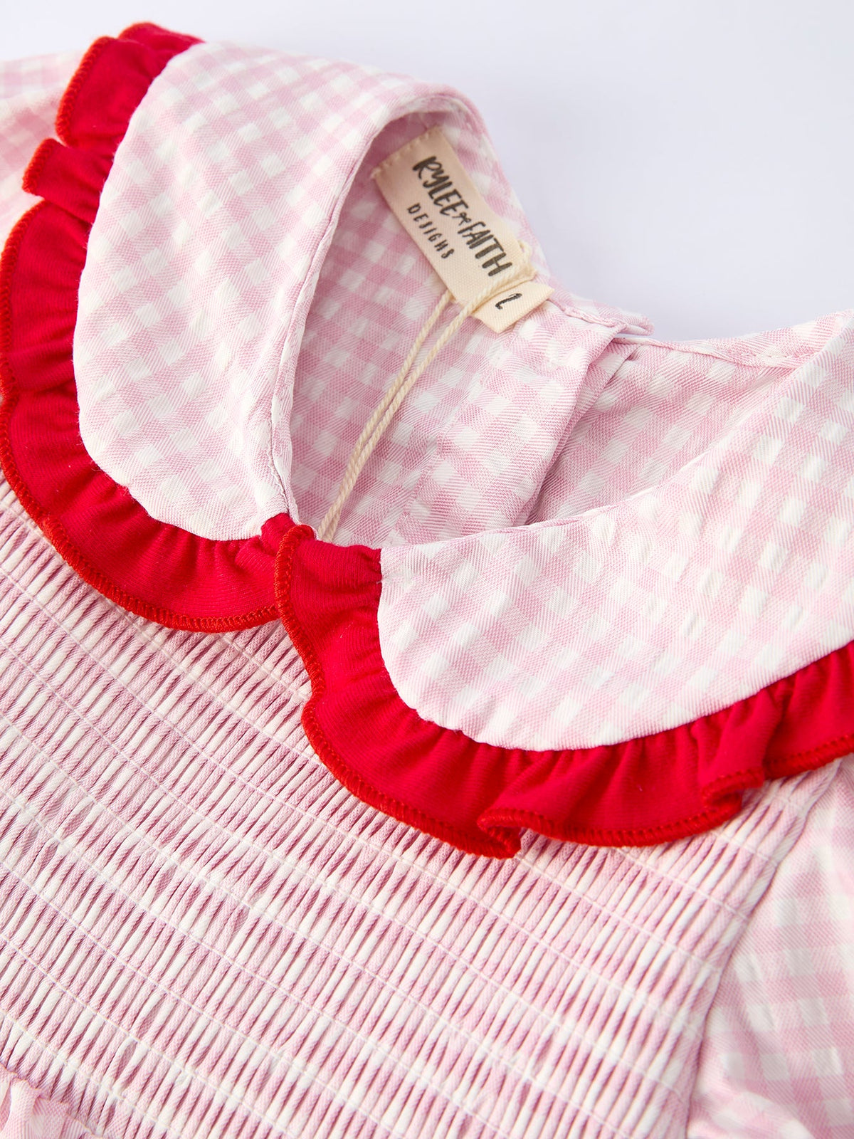 close-up of Rylee Faith Designs girls strawberry smocked dress with pink gingham pattern and red ruffled collar