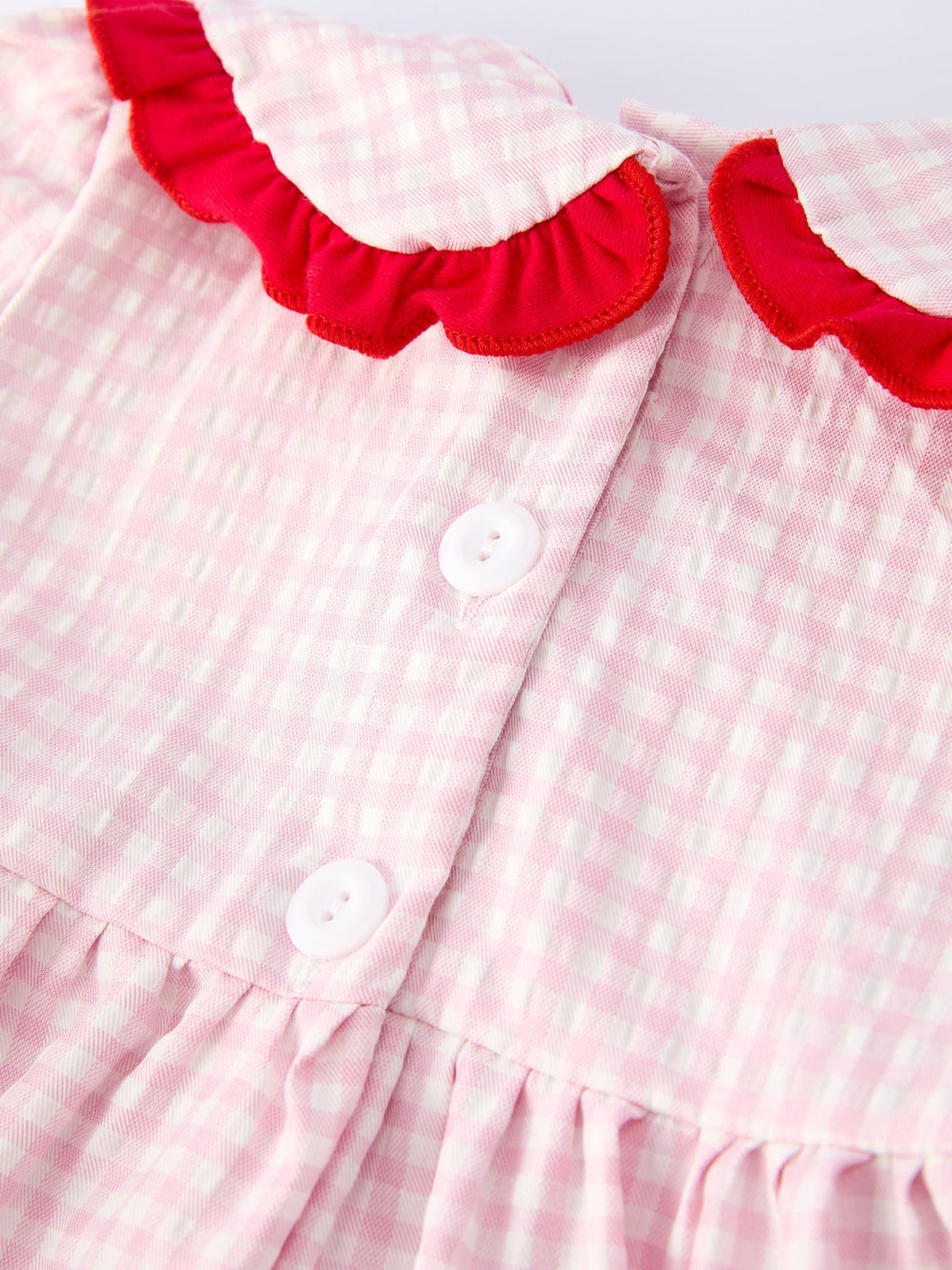 Close-up of pink and white gingham girls strawberry smocked dress with red ruffle collar and white buttons