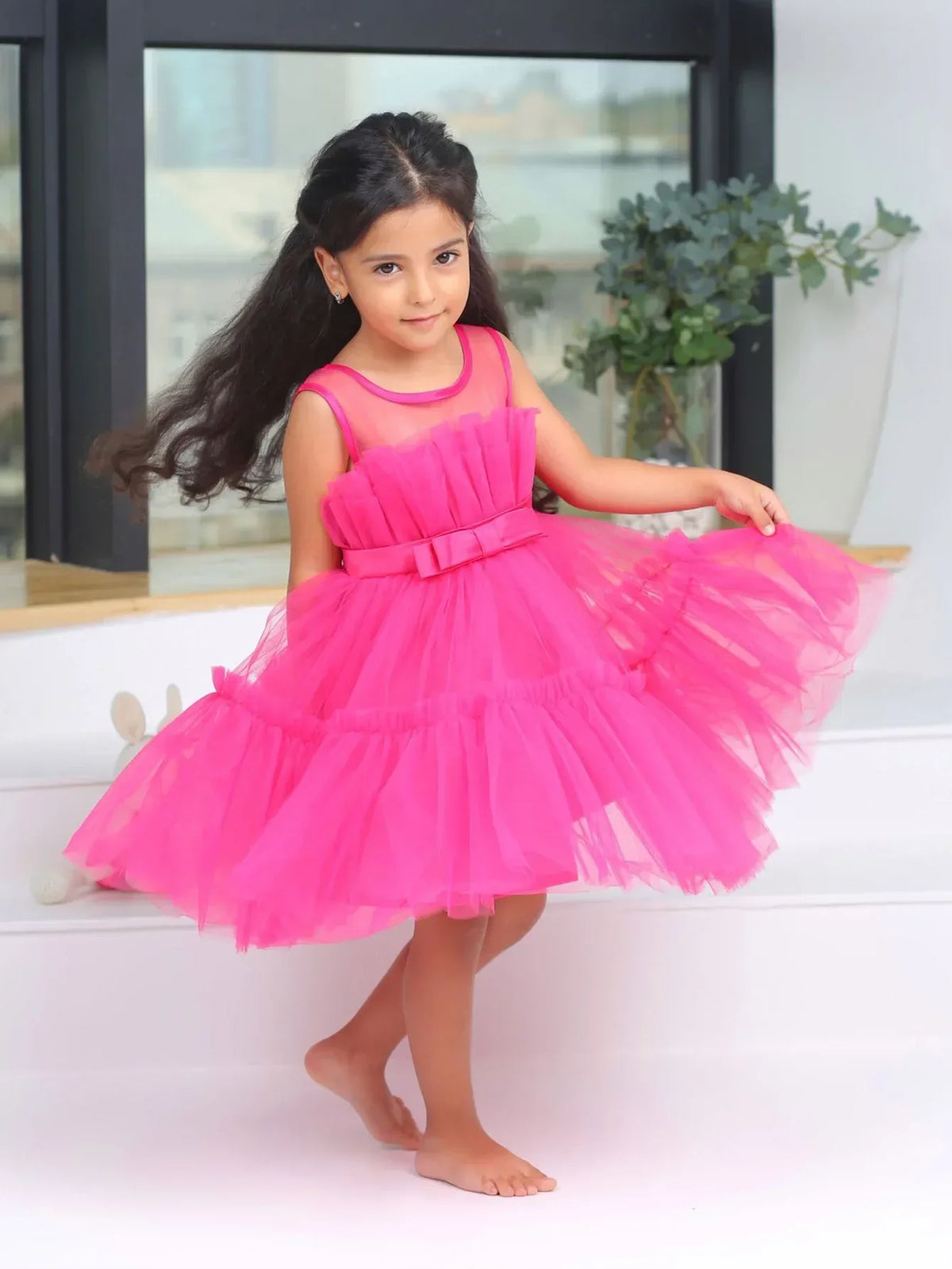 Pink girls tulle occasion dress with bow detail worn by young girl for special events