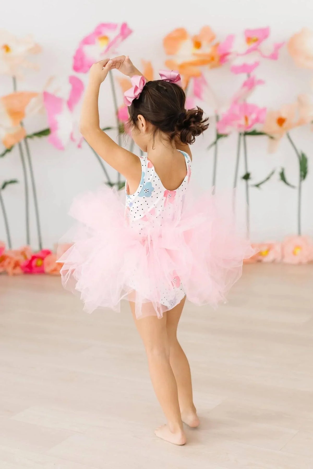 Young girl wearing pink Mila & Rose girls tutu leotard twirling with arms raised in dance pose