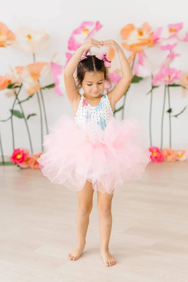 Young girl wearing pink girls tutu leotard standing in ballet pose with arms overhead