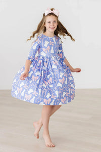 Young girl wearing blue Mila & Rose girls twirl dress with pockets spinning barefoot indoors