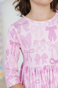 Girl wearing pink girls twirl dress with pockets featuring bow patterns in size 3 4