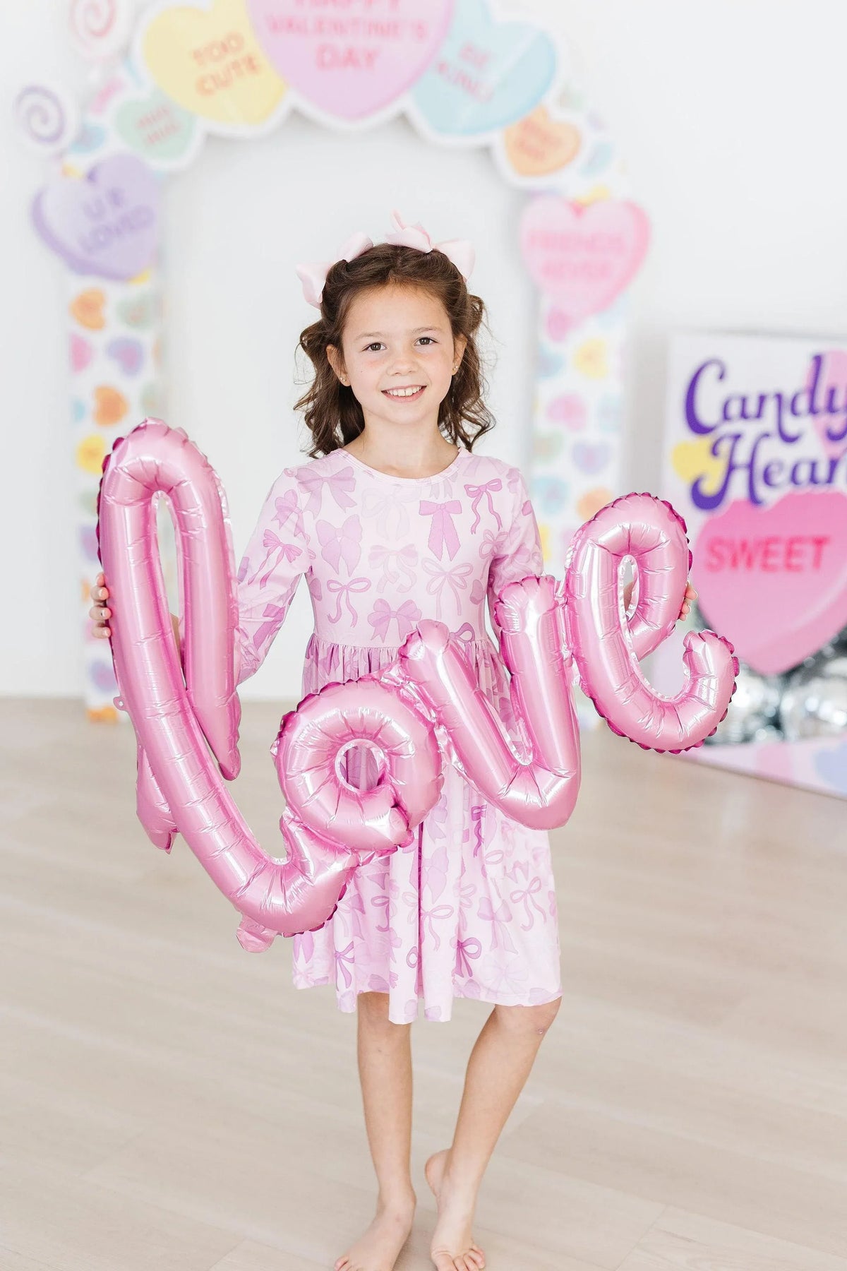 Young girl wearing pink Mila & Rose girls twirl dress with pockets holding pink love balloon