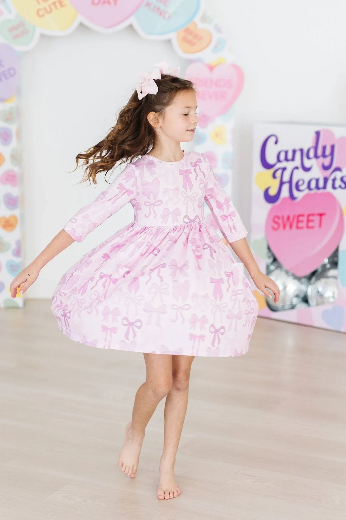 Young girl wearing pink girls twirl dress with pockets spinning inside a decorated room