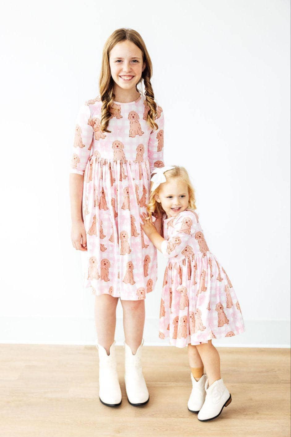 Two girls wearing pink goldendoodle twirl dress for girls posing and smiling indoors