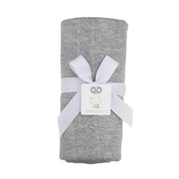 soft gray knit baby blanket rolled and tied with a white ribbon for newborns