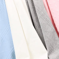 White baby knit blanket made of soft cotton material among pastel blue, gray, and pink baby blankets