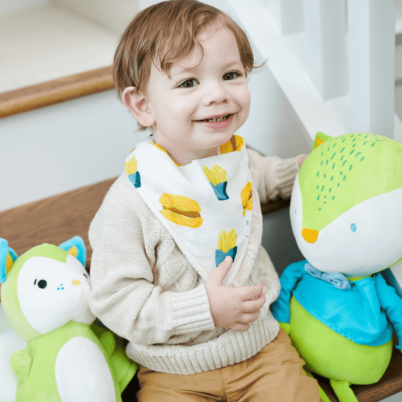 Happy toddler wearing the Small Fry and Burgers and Fries 2 Pack Muslin & Terry Cloth Bib Set while playing with stuffed animals.