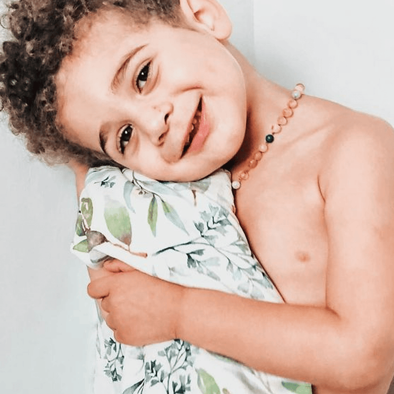 A joyful child hugging the Basil Bear Mint Applique Baby Blanket, highlighting its soft and cozy texture.