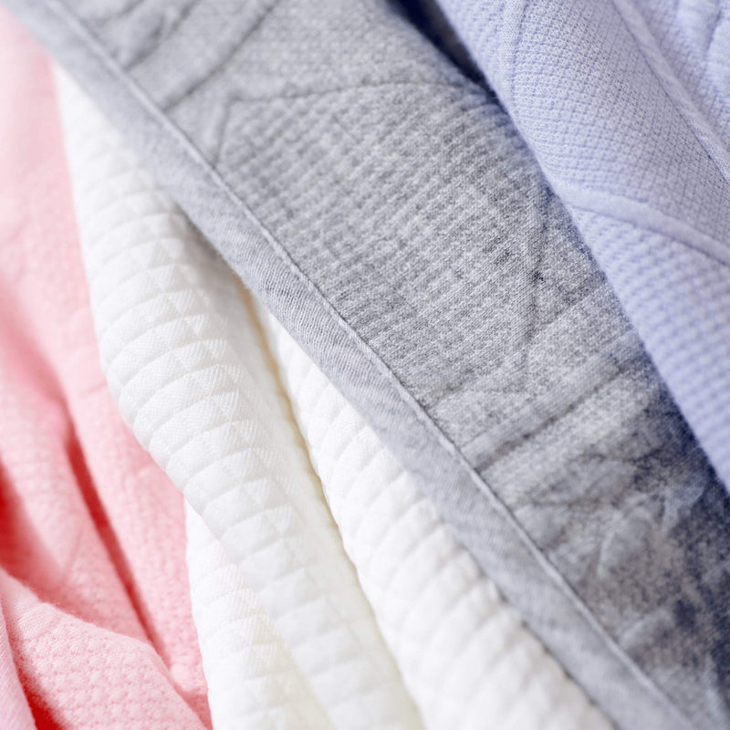 A colorful collection of blankets including the Gray Knit Blanket by Goosewaddle®, showcasing its stylish design and variety of colors for nursery decor.