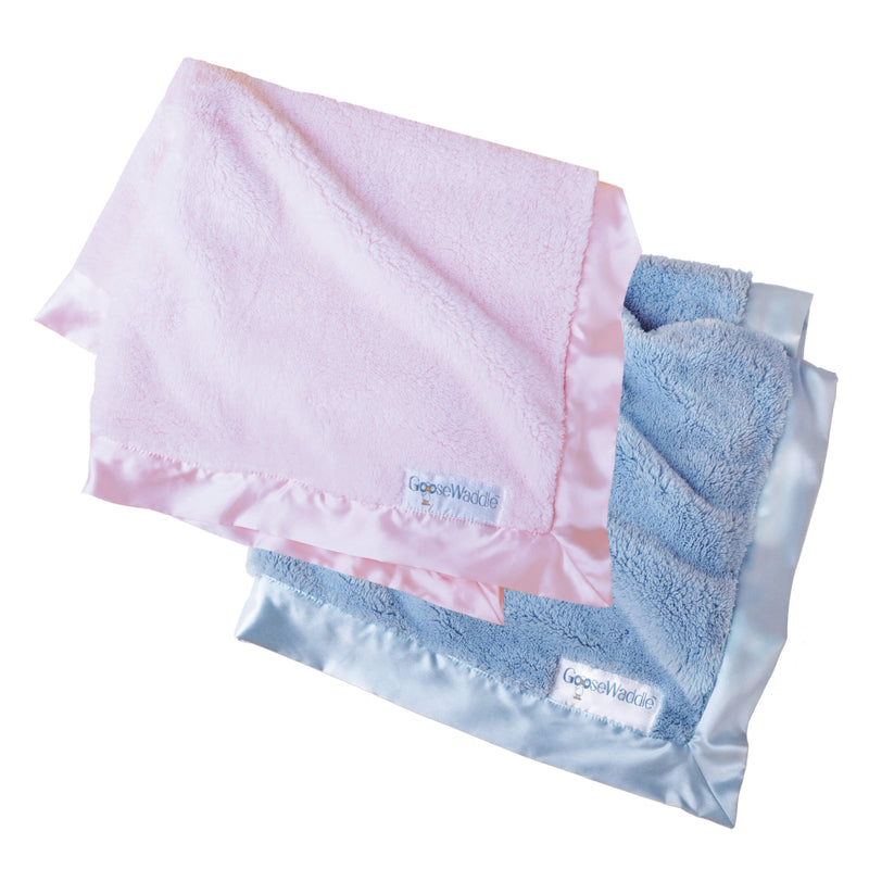 Set of GooseWaddle Luxury Blankets in pastel pink and soft blue, showcasing the luxurious texture and satin edges, ideal nursery essentials.