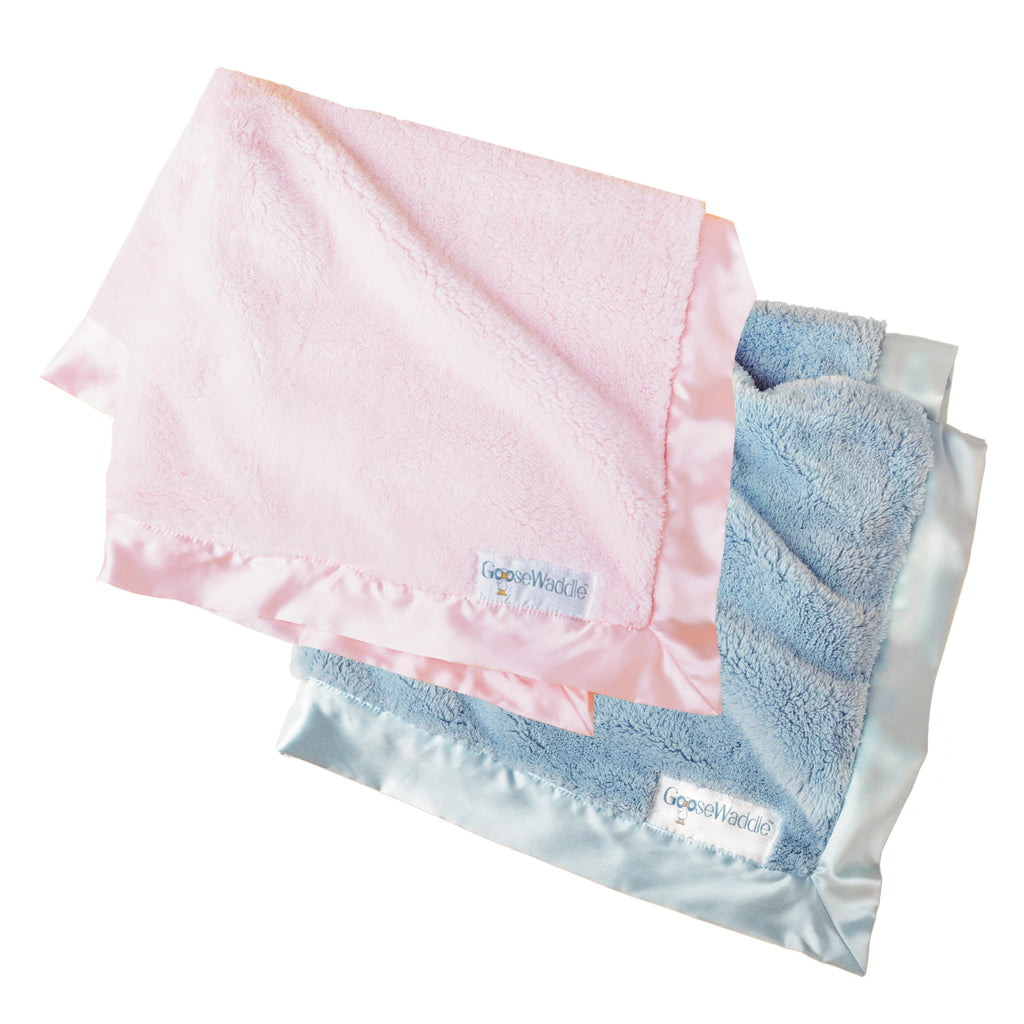 GooseWaddle Luxury Blanket in pastel pink and serene blue, showcasing soft textures and silky satin edges, perfect for newborns
