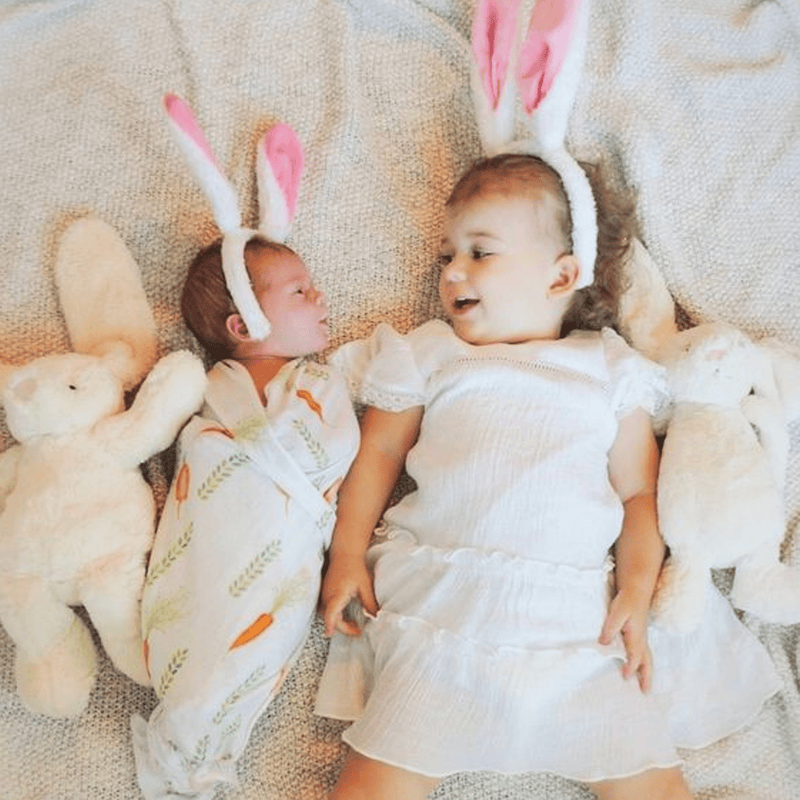 2 PK Newborn Receiving Blankets by Goosewaddle® with two adorable children wearing bunny ears surrounded by soft toys, showcasing the blankets' playful nature.