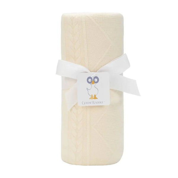 Oatmeal knit baby blanket rolled and tied with white ribbon for newborns