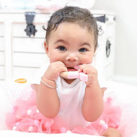 Baby holding soft silicone and wood pink bunny teether while wearing pink tutu dress