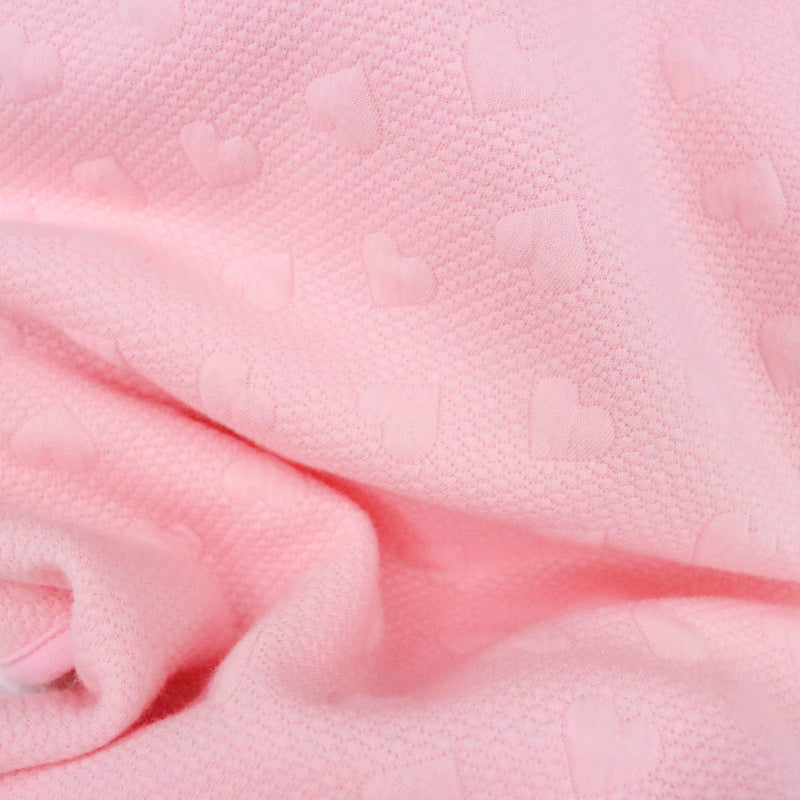 Close-up of the soft texture of the Pink Knit Blanket showcasing its heart pattern, perfect for delicate baby skin.