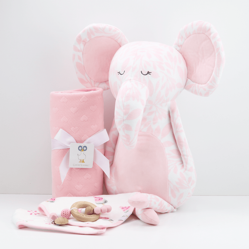 Poppy Elephant Pink Super Soft Plush alongside a cozy pink blanket and baby accessories, perfect for newborns, offering comfort and companionship for little ones.