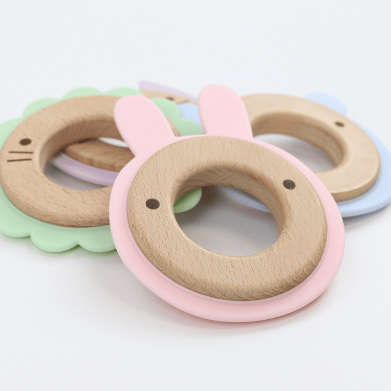 Colorful assortment of silicone and wood teethers including the Pink Bunny Silicone + Wood Teether, designed for babies for teething relief and sensory exploration.