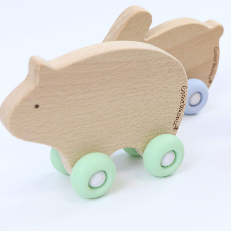 Two Silicone + Wood Teethers with Wheels lined up, featuring a natural wood finish and colorful wheels, designed for babies 4 months and older.
