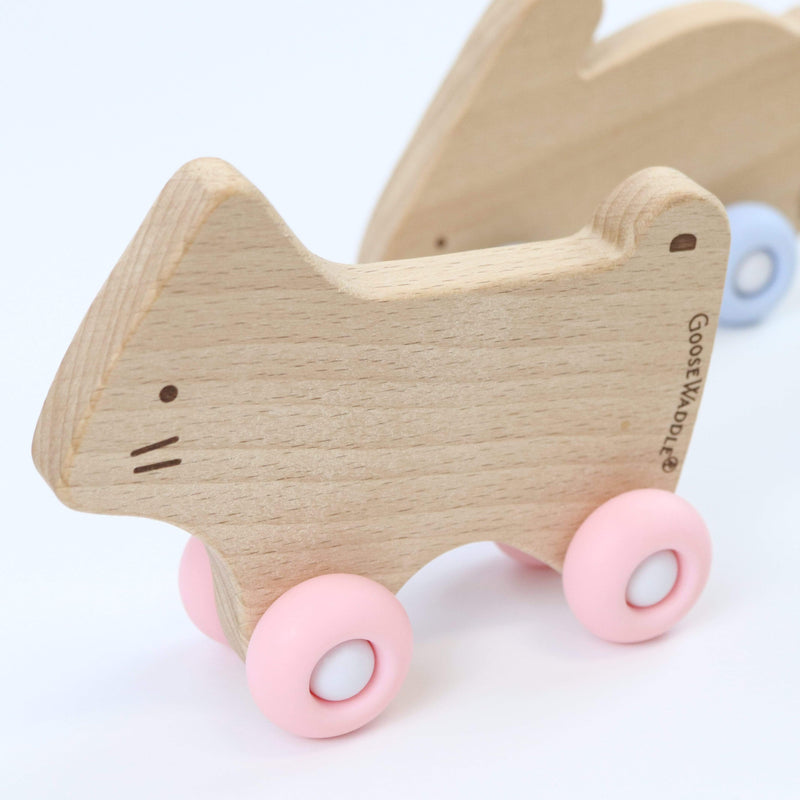 Silicone + Wood Teether with Wheels in a playful wooden dog design, equipped with pink rolling wheels for engaging baby play.
