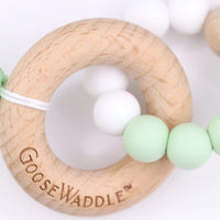 Mint wooden and silicone teether with white beads and natural oak ring for soothing sore gums in babies.