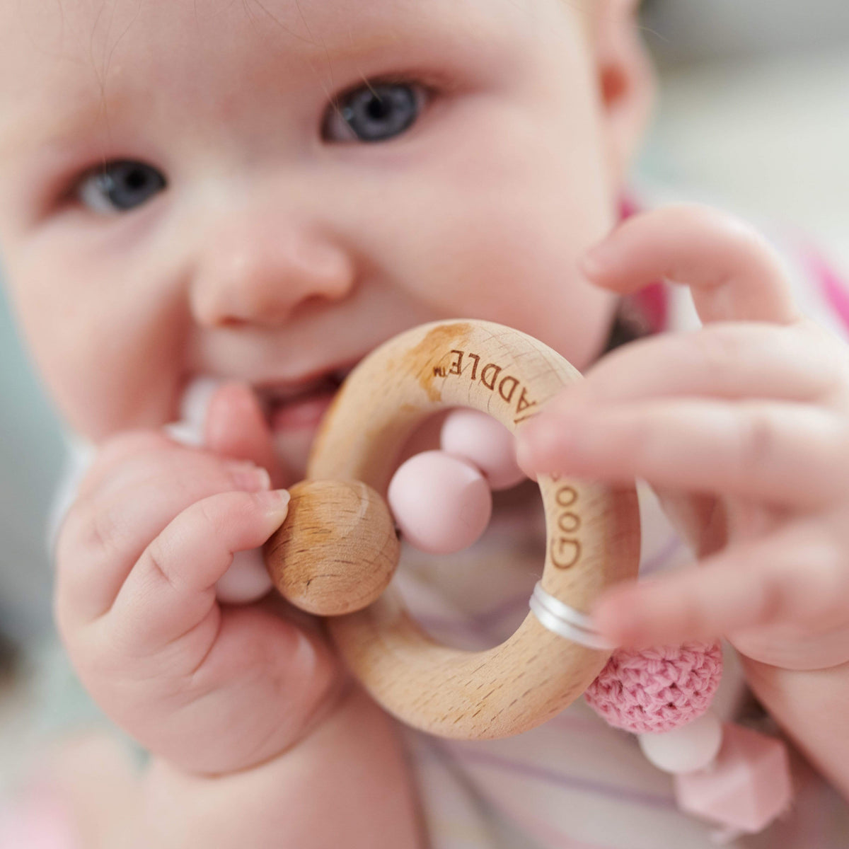 Wooden and Silicone Teether - Pink: baby holds ring teether with pink beads and snap clasp