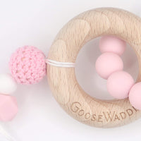 Wooden and Silicone Teether - Pink: a wooden ring with pink silicone beads and a crocheted pink ball, clip-fastened.