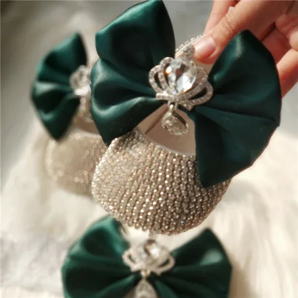 green headpiece set for babies with large satin bows and rhinestone crown embellishments