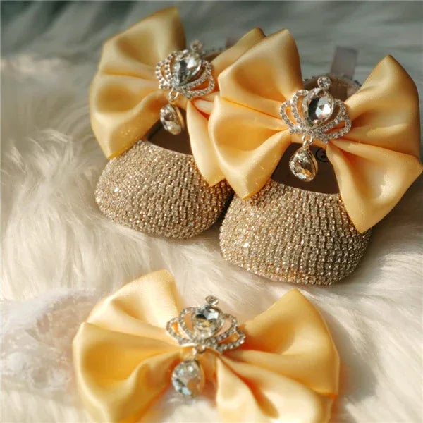 gold glitter baby shoes and yellow satin bow headpiece set for babies with rhinestone crown detail