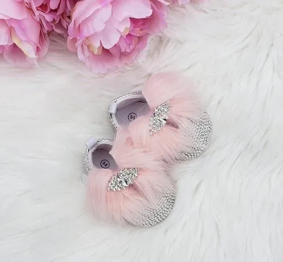 pink baby shoes with rhinestone details and pink fluff for infants near pink flowers