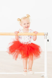 Toddler girl wearing a holiday red tutu leotard for girls with 3/4 sleeves holding ballet barre
