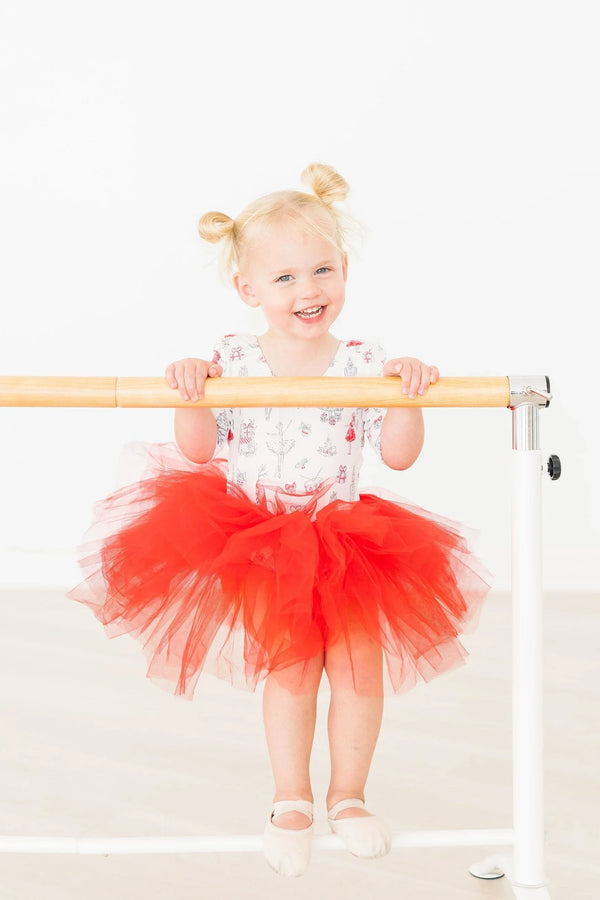Toddler girl wearing a holiday red tutu leotard for girls with 3/4 sleeves holding ballet barre